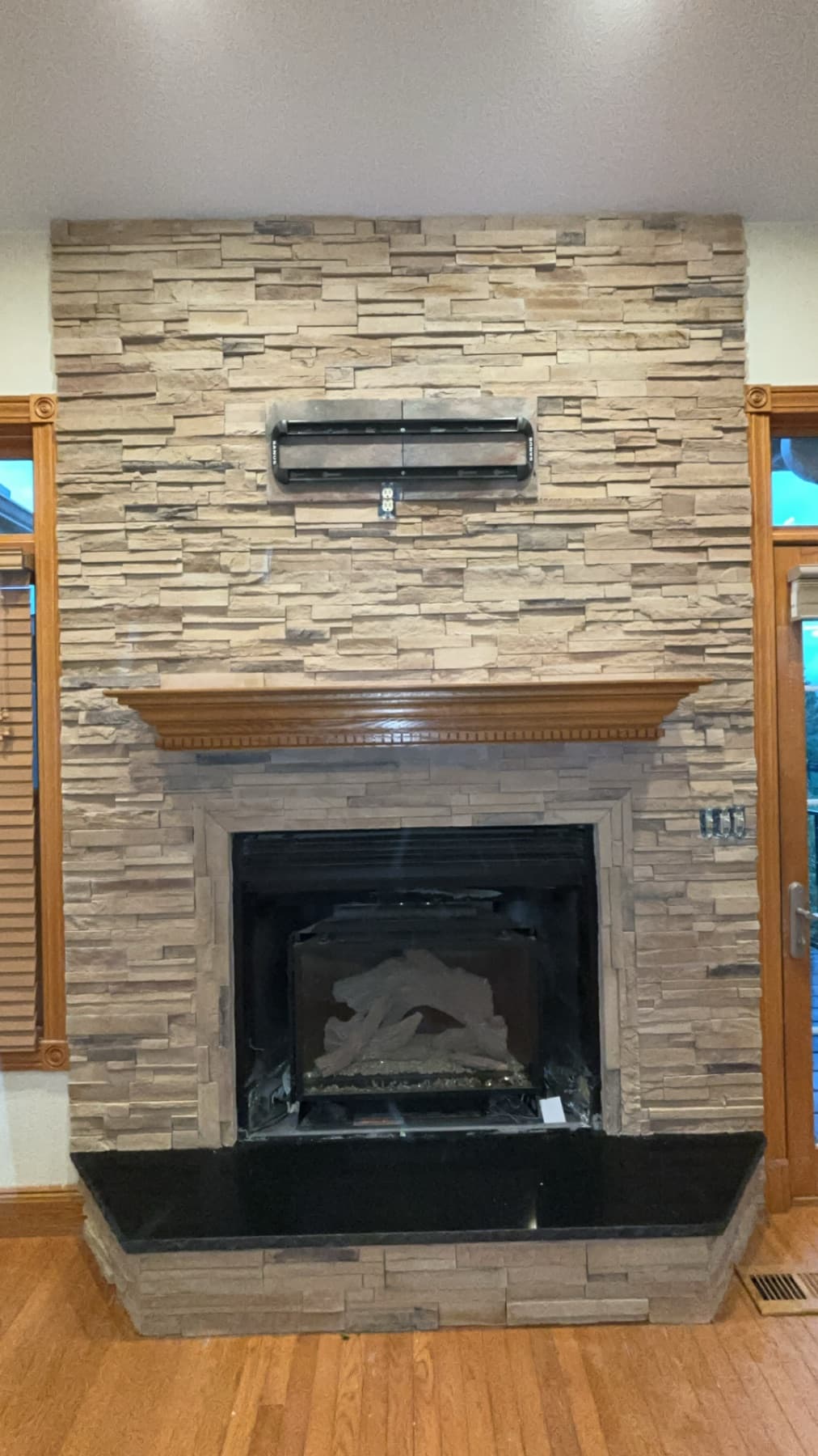 Stacked stone fireplace with wood mantel